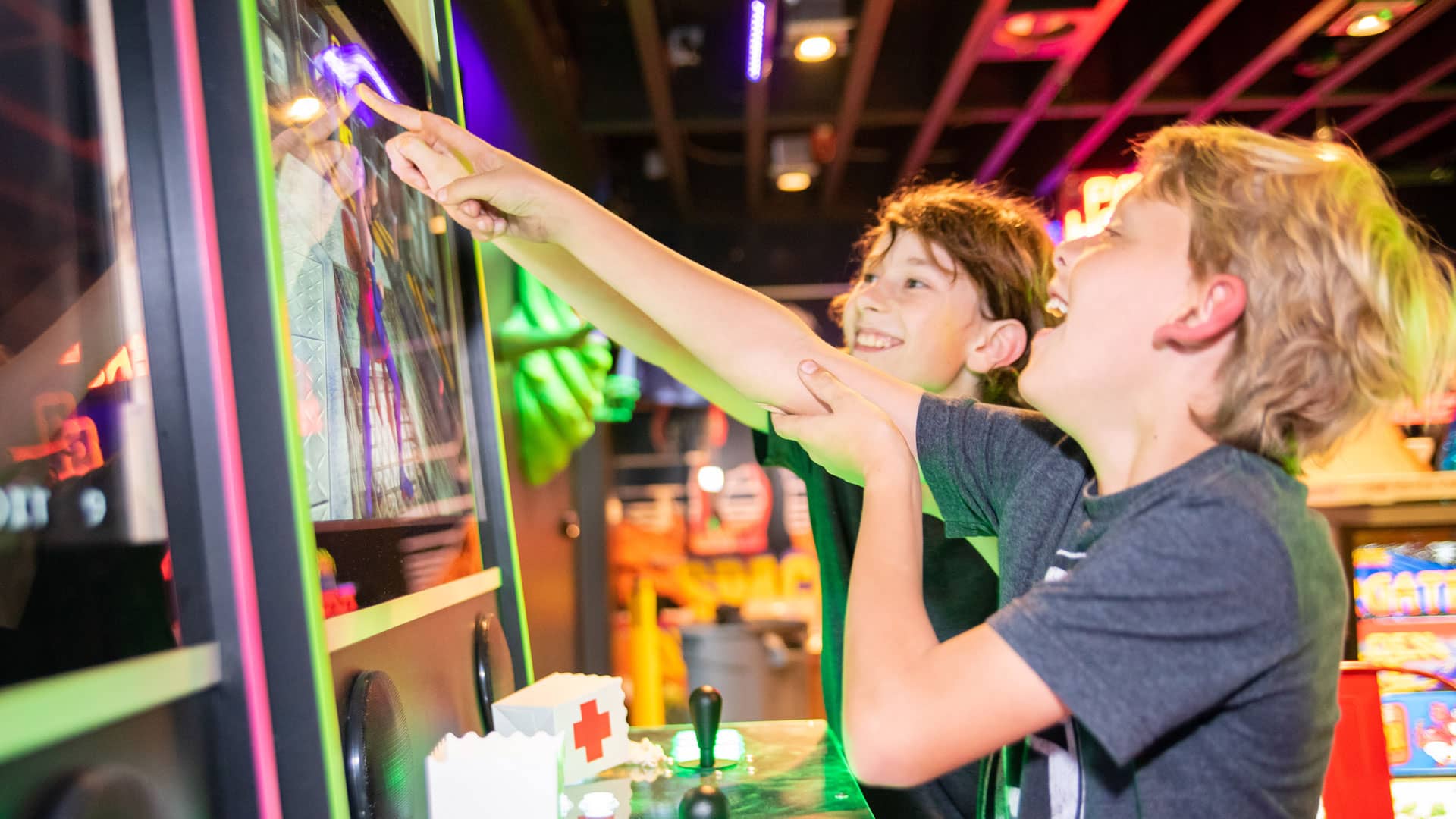 Two teens playing an arcade laughing